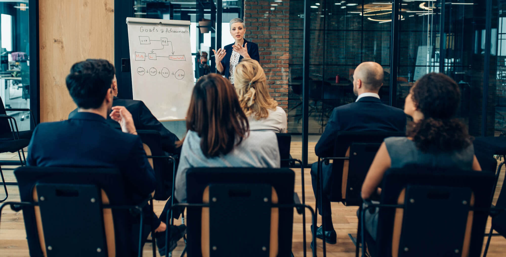 Serious businesswoman giving presentation to multi-ethnic business group with flipchart